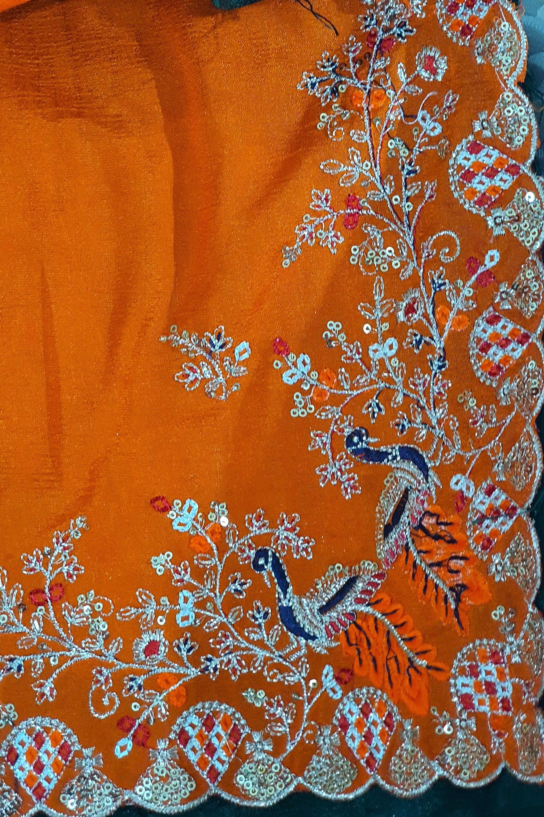 Orange fabric with intricate floral and peacock embroidery